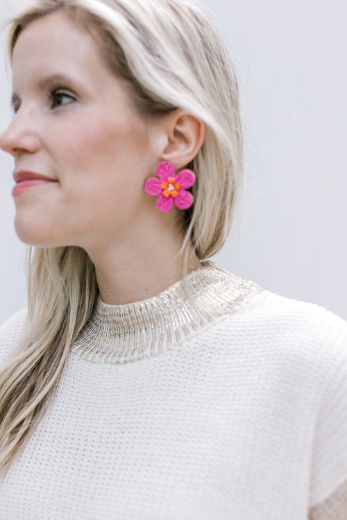 Close up of Model wearing pink straw daisy earrings with orange and pearl details.