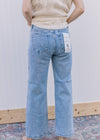 Back view of Model wearing light wash jeans with daisy embroidery and slightly cropped fit.
