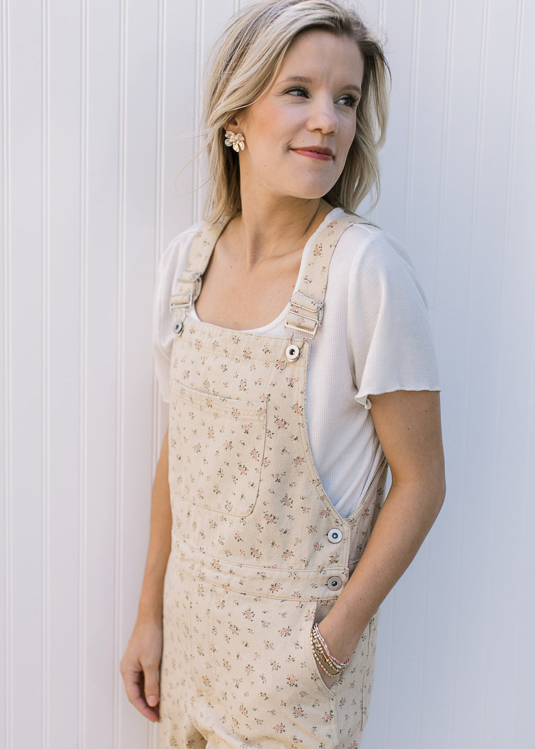 Model wearing cream overalls with ditsy floral, adjustable straps and a front pouch pocket.