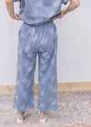 Back view of Model wearing denim color pants with light blue dandelions and elastic waist.