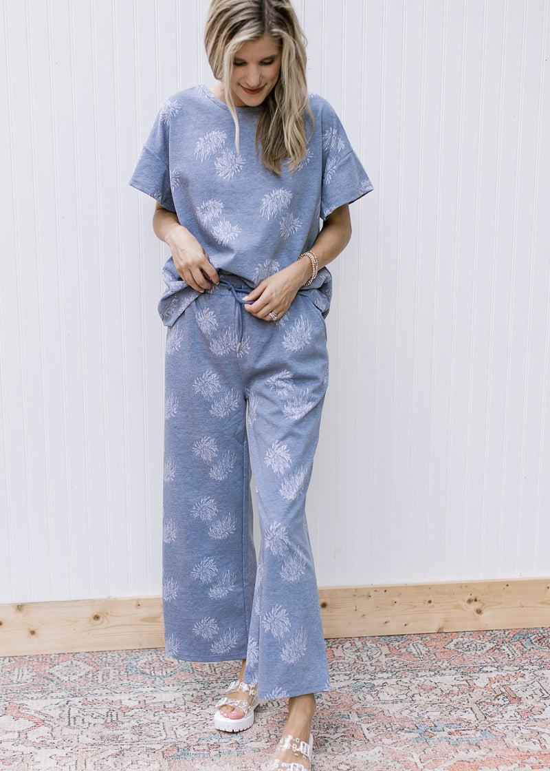 Model wearing a denim color pants with light blue dandelions and a matching top.