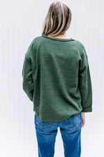 Back view of Model wearing a deep olive top with a v-neck and cuffed sleeves.