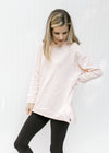 Model wearing black leggings and a blush colored hoodie with long sleeves and two side zippers. 
