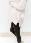 View of the zipper on the side of a blush colored sweatshirt with long sleeves and a hood. 