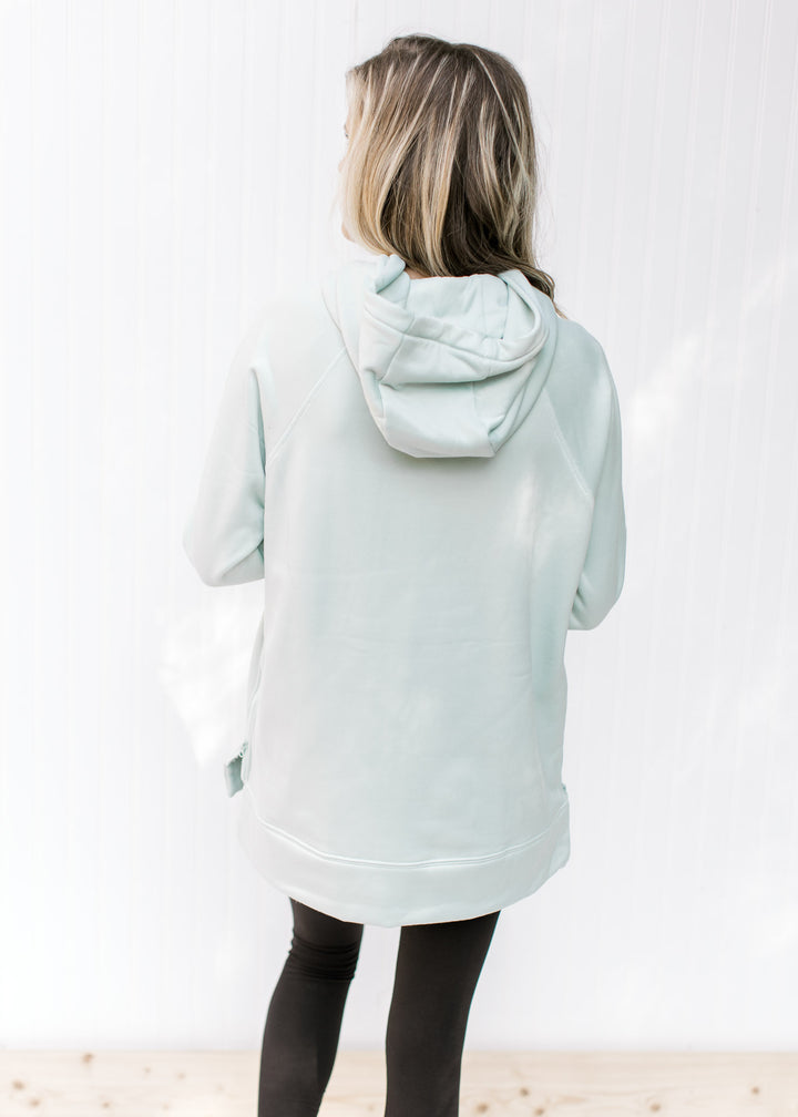 Back view of Model wearing a mint colored hoodie with long sleeves and a side zippers.