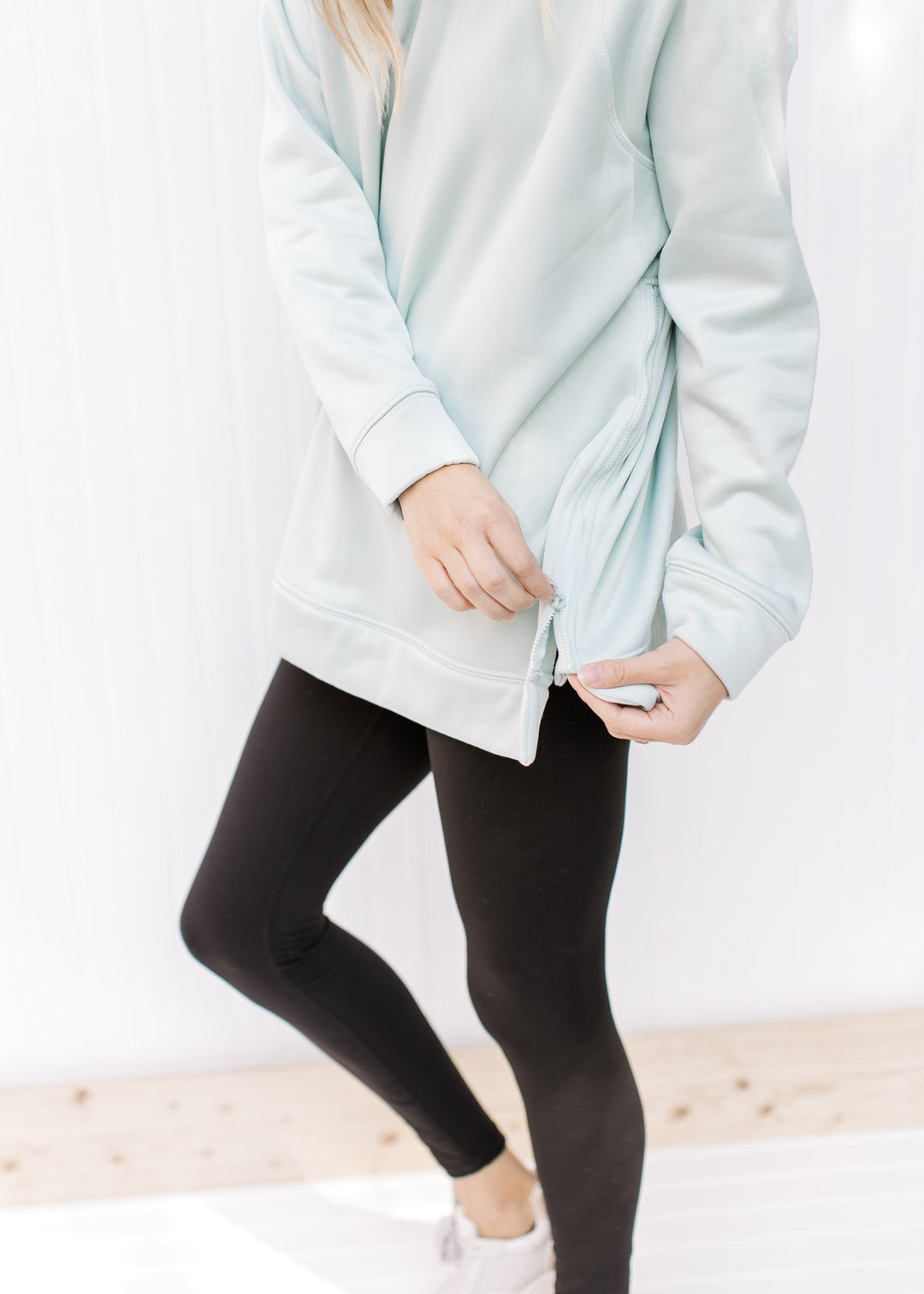 Close up of side zipper on a mint colored hoodie with long sleeves and a hoodie. 