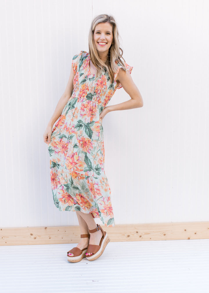 Model wearing heels with a pale green midi dress with a floral pattern and a smocked bodice.
