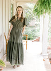 Model wearing an olive maxi with an elastic waist, short sleeves, pockets and an eyelet detail.