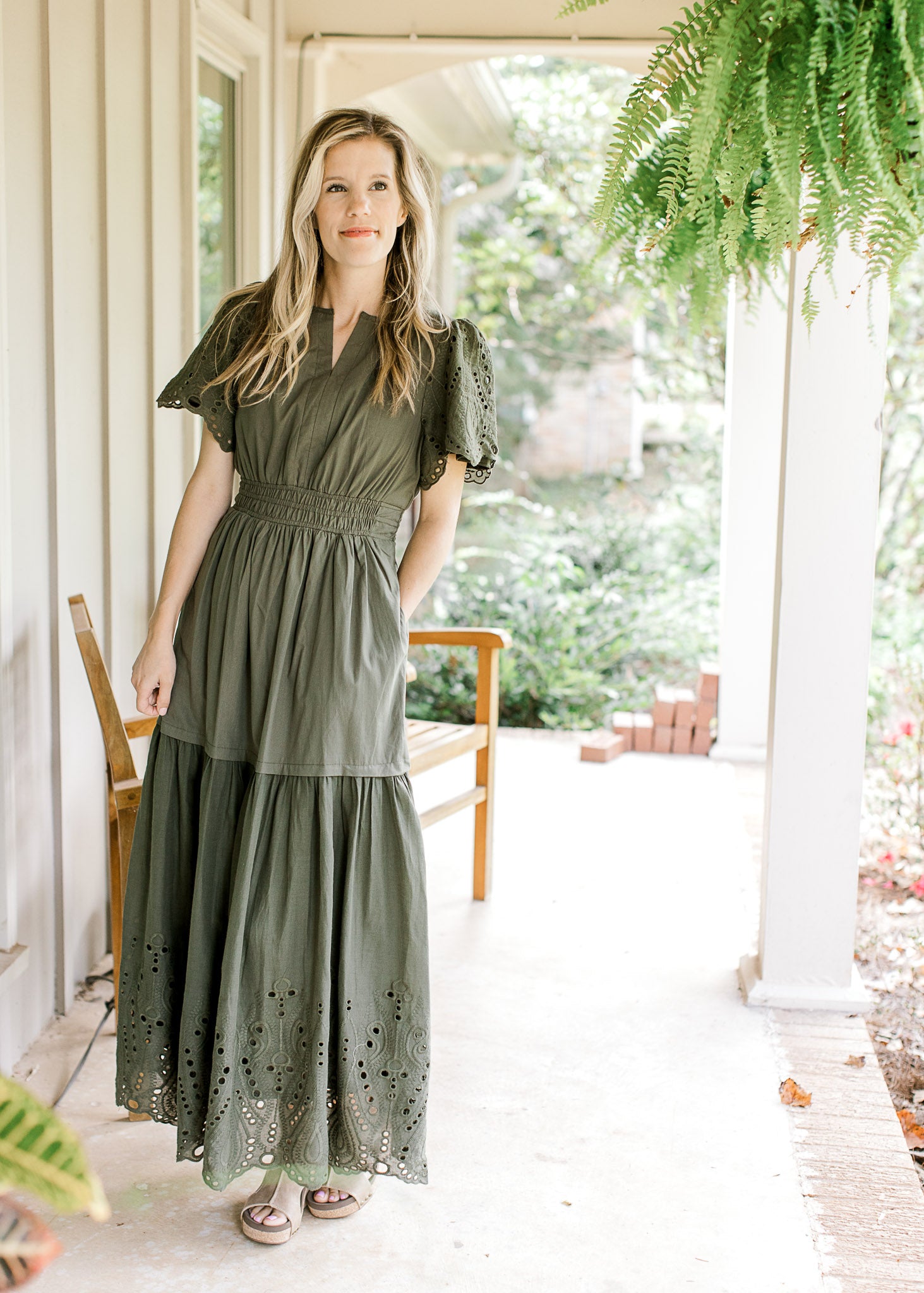 Model wearing an olive maxi with an elastic waist, short sleeves, pockets and an eyelet detail.