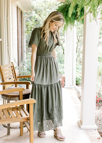 Model wearing wedges with an olive maxi with an elastic waist and short sleeves. 
