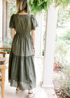 Back view of Model wearing an olive maxi with an elastic waist and eyelet detail at sleeve and hem. 