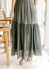 Close up of eyelet detail along the hem of an olive maxi with an elastic waist and short sleeves.