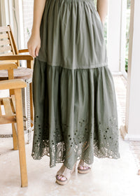Close up of eyelet detail along the hem of an olive maxi with an elastic waist and short sleeves.