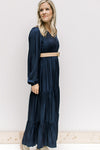 Model wearing a navy maxi with a v-neck and long sleeves with an elastic cuff and a camel belt.