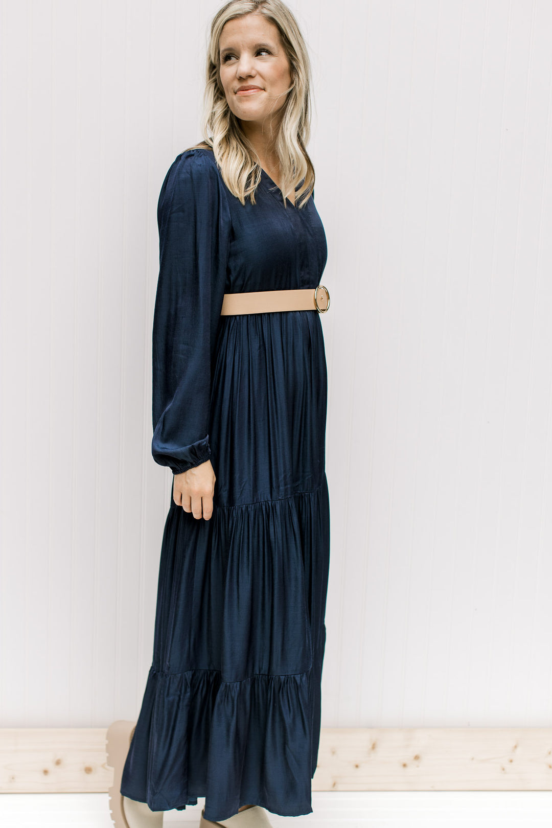 Model wearing a navy maxi with a v-neck and long sleeves with an elastic cuff and a camel belt.