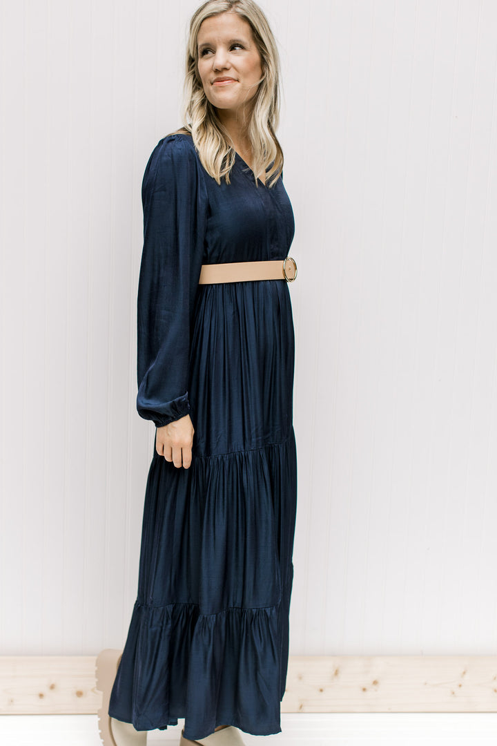 Model wearing a navy maxi with a v-neck and long sleeves with an elastic cuff and a camel belt.