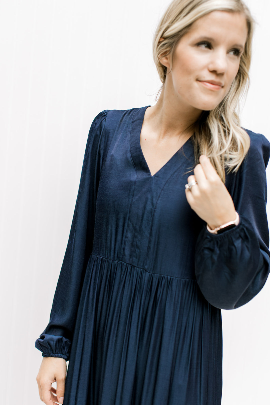 Close up of v-neck and long sleeve with elastic cuff on a navy tiered maxi comprised of polyester. 