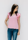 Model wearing jeans with a polyester pink v-neck top with tiered ruffle short sleeves. 