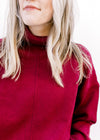 Close up of turtleneck on a deep red sweater with long sleeves and ribbed sleeve and hem. 