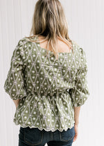 Back view of Model wearing a sage top with white embroidery, 3/4 sleeves and a square neck.