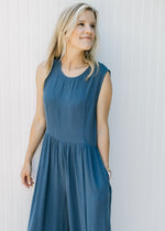 Close up of round neck and pockets on a navy sleeveless jumpsuit with wide legs.