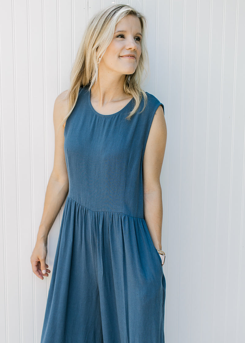 Close up of round neck and pockets on a navy sleeveless jumpsuit with wide legs.