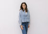 Model wearing jeans with a light denim top with a deep V, long sleeves and a raw hemline.