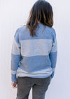 Back view of Model wearing a light blue and white color block, ribbed sweater with long sleeves. 
