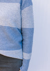 Close up of ribbing on a light blue and white color block sweater with long sleeves. 