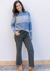 Model wearing jeans with a light blue and white ribbed sweater with long sleeves. 