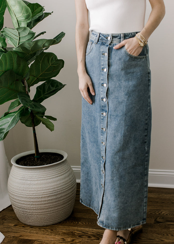 Model wearing a medium wash maxi denim skirt with button front, pockets and a slight stretch.
