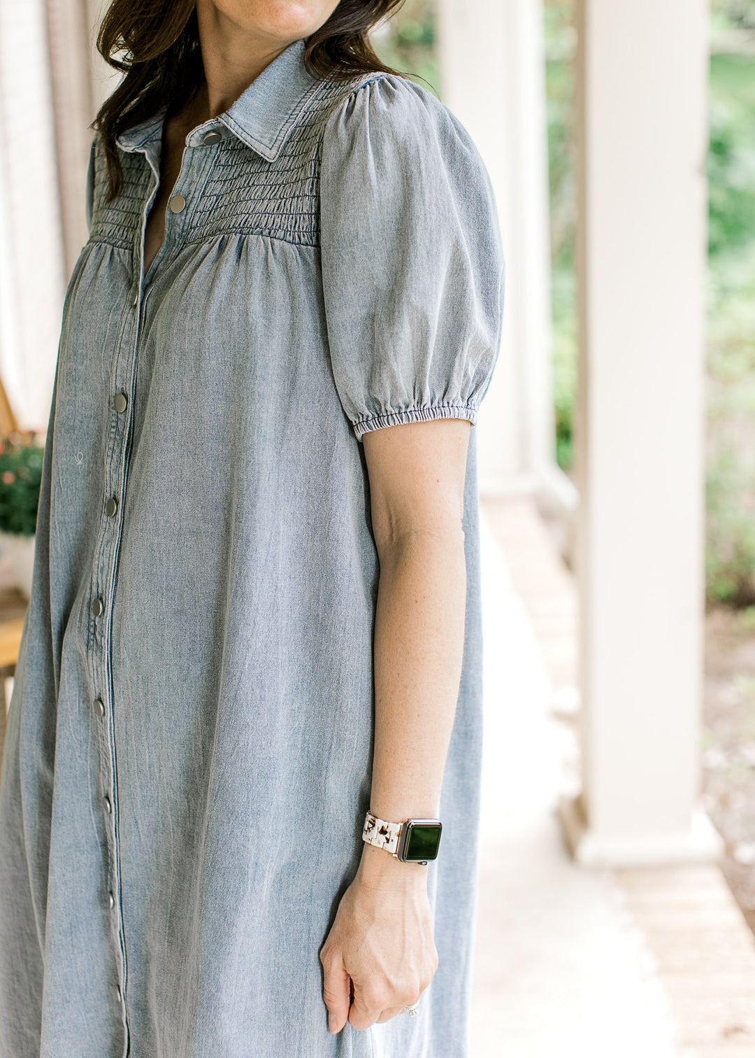 Close up view of bubble short sleeves on a light wash denim dress with a smocked yolk and buttons.