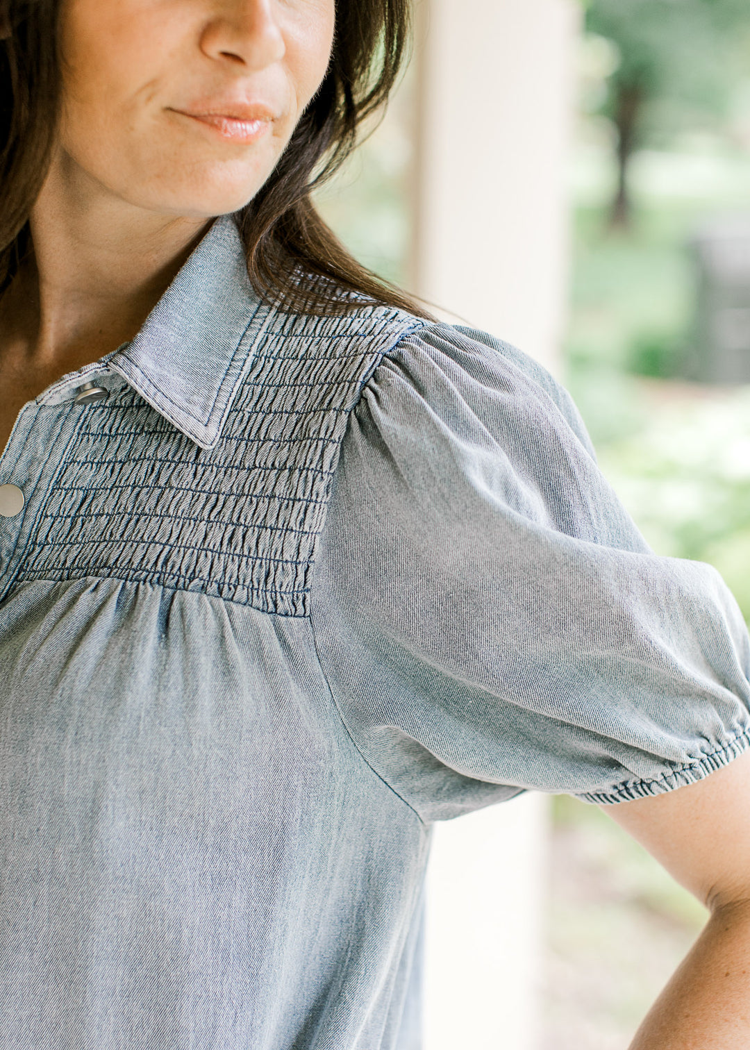 Close up of smocked yolk and collar on a light wash denim dress with bubble short sleeves. 