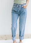 Model wearing medium washed straight leg jeans with a criss cross closure at waistband. 