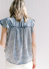 Back view of Blonde model wearing a acid washed denim top with short sleeves and button front. 