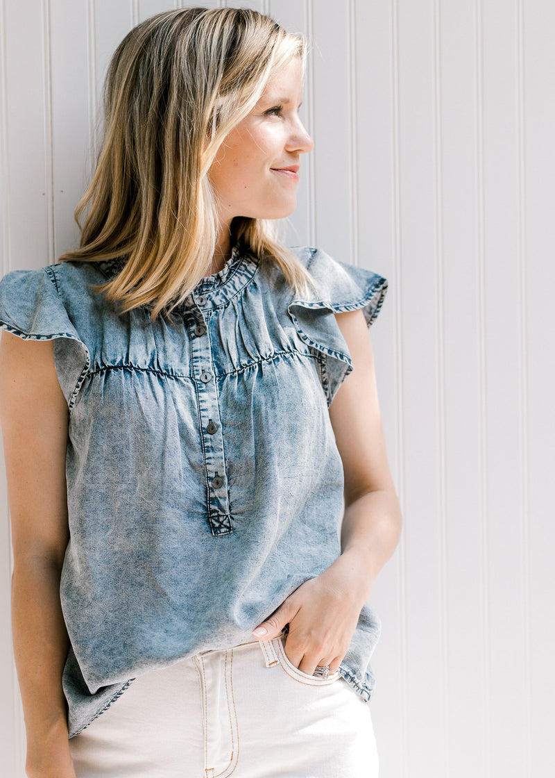 Blonde model wearing white jeans with an acid washed denim top with short sleeves and button front. 