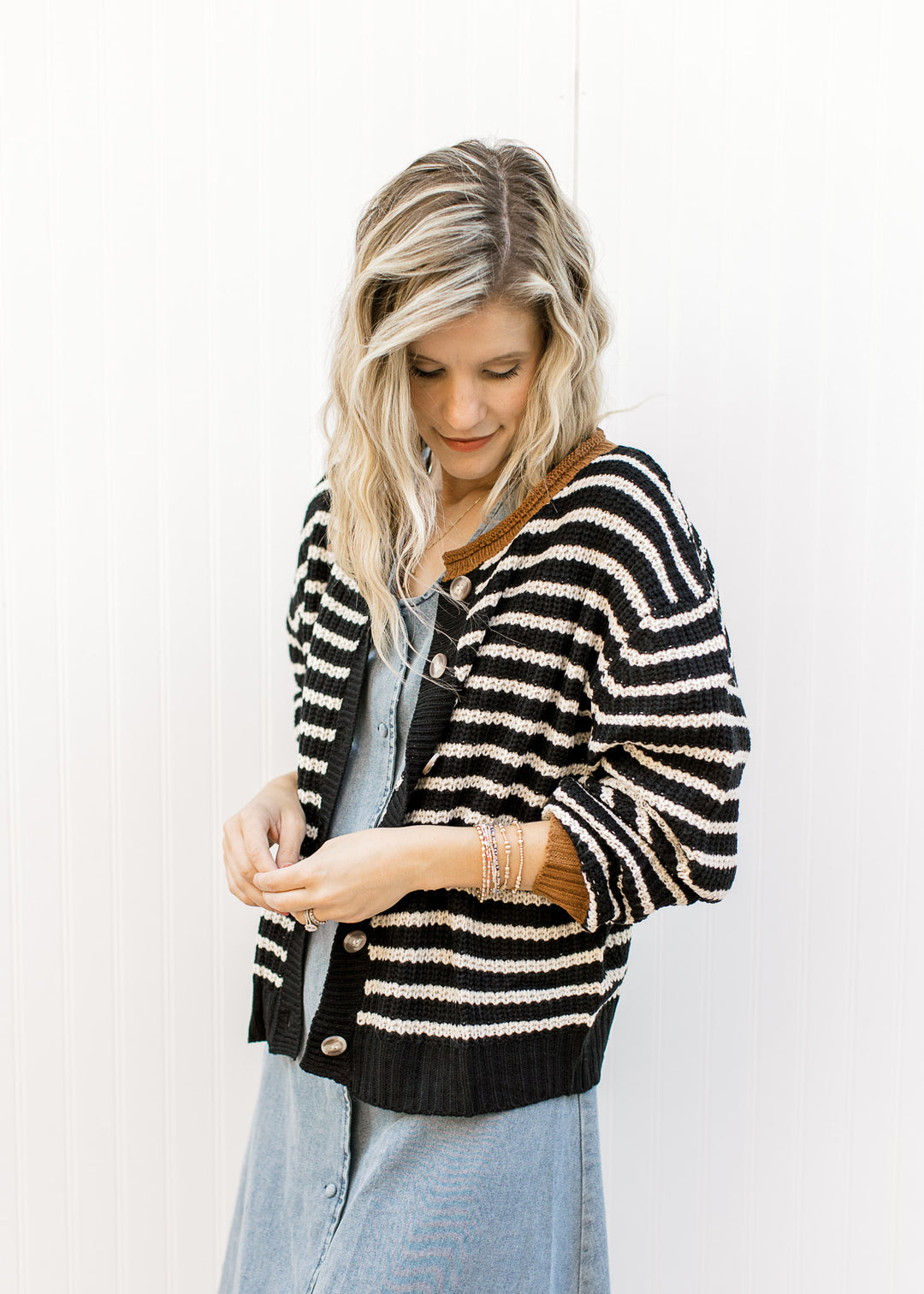 Model wearing a black and white striped sweater over a denim button up midi with a v-neck. 