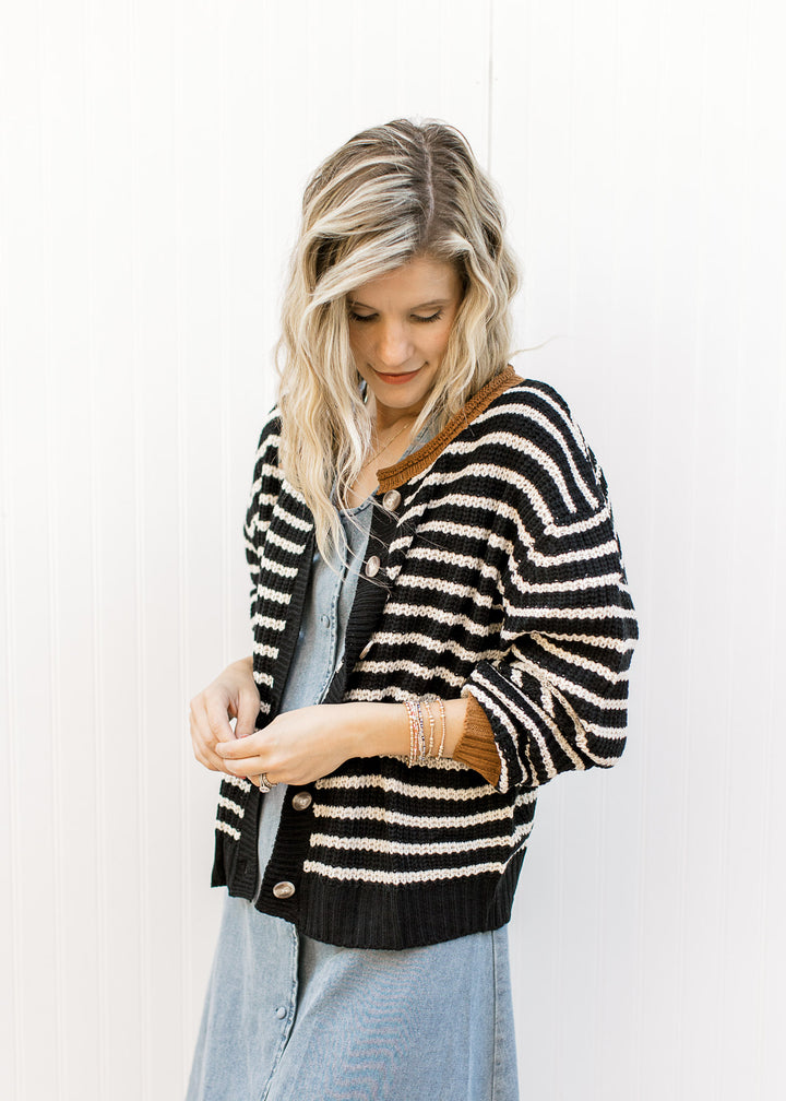 Model wearing a black and white striped sweater over a denim button up midi with a v-neck. 