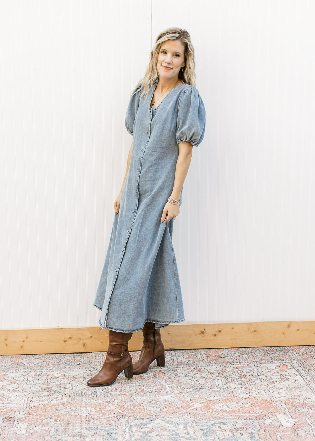 Model wearing booties and a medium colored denim midi with bubble short sleeves and a v-neck. 