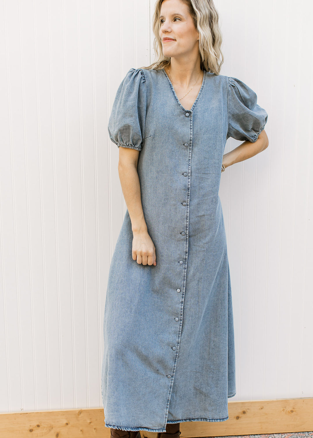 Model wearing a medium colored denim midi with bubble short sleeves, v-neck and button front. 