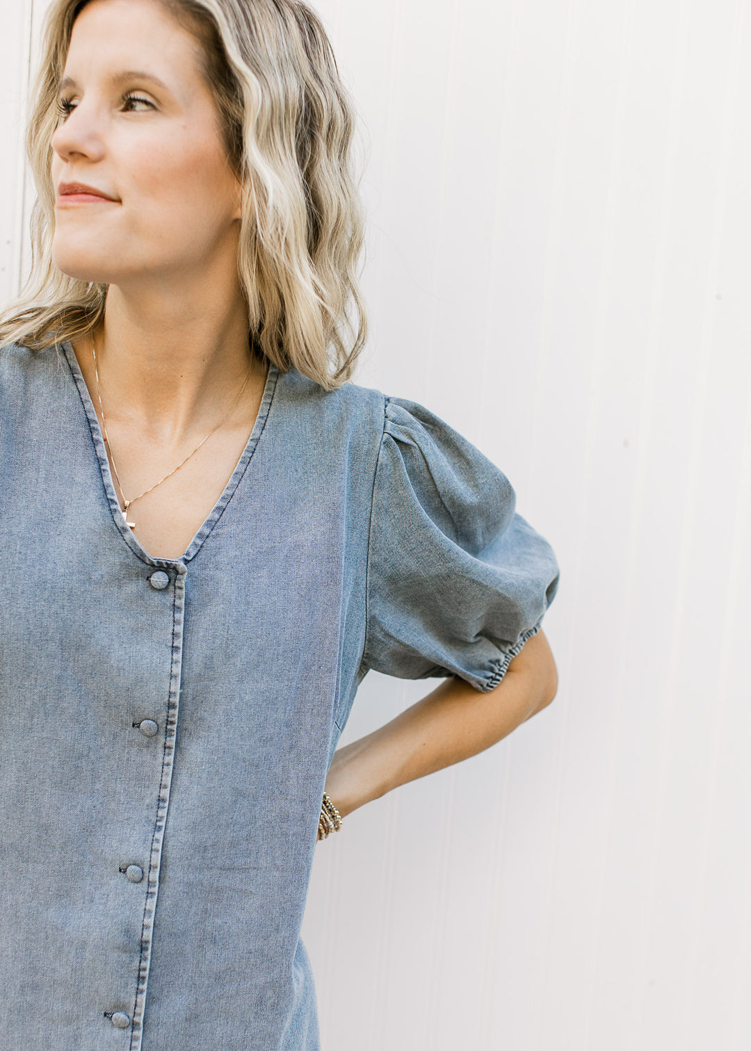 Close up of v-neck, bubble short sleeves and button front on a medium washed midi. 