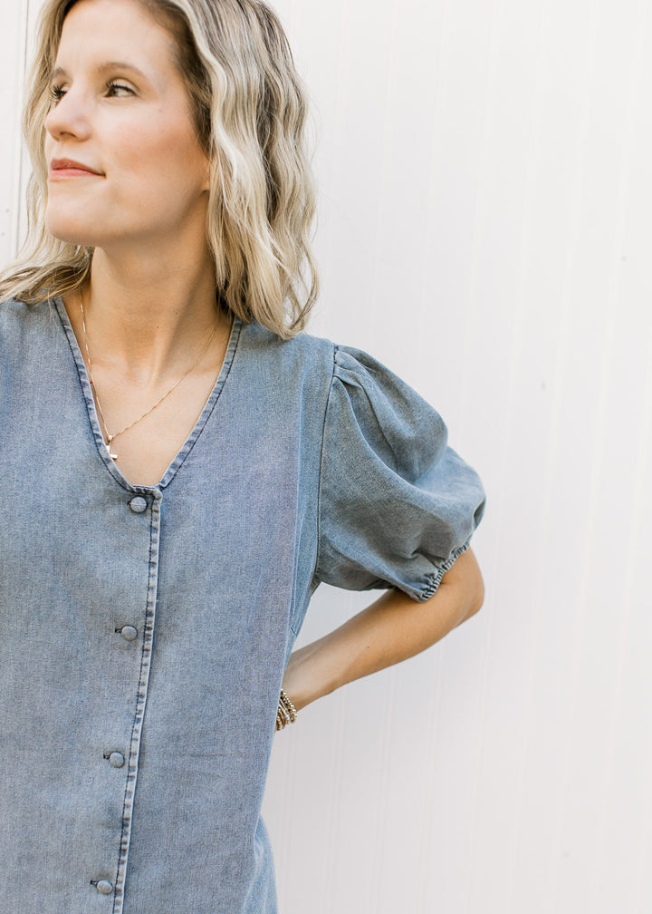 Close up of v-neck, bubble short sleeves and button front on a medium washed midi. 