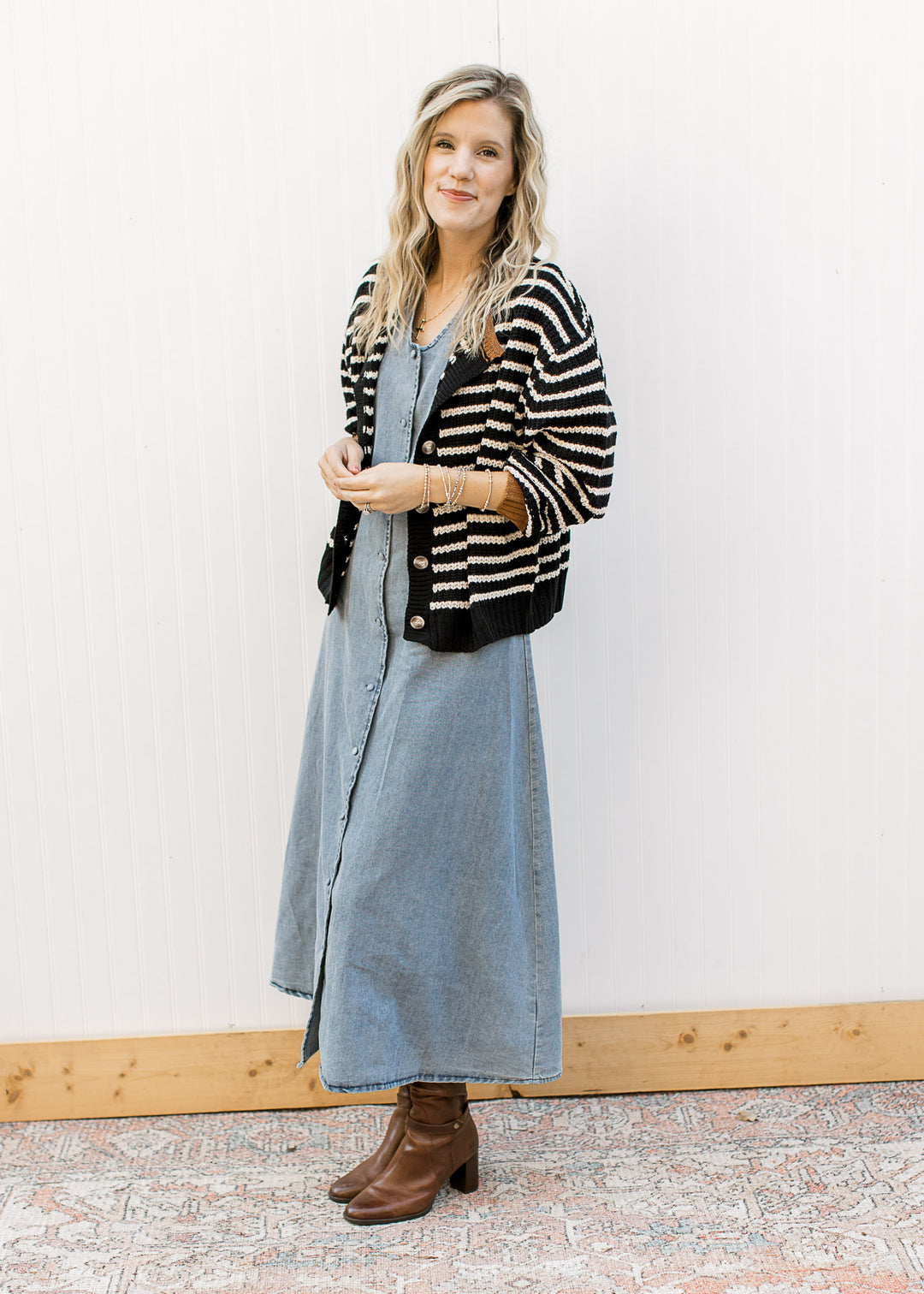 Model wearing stripped cardigan, boots and a denim midi with v-neck and button front. 