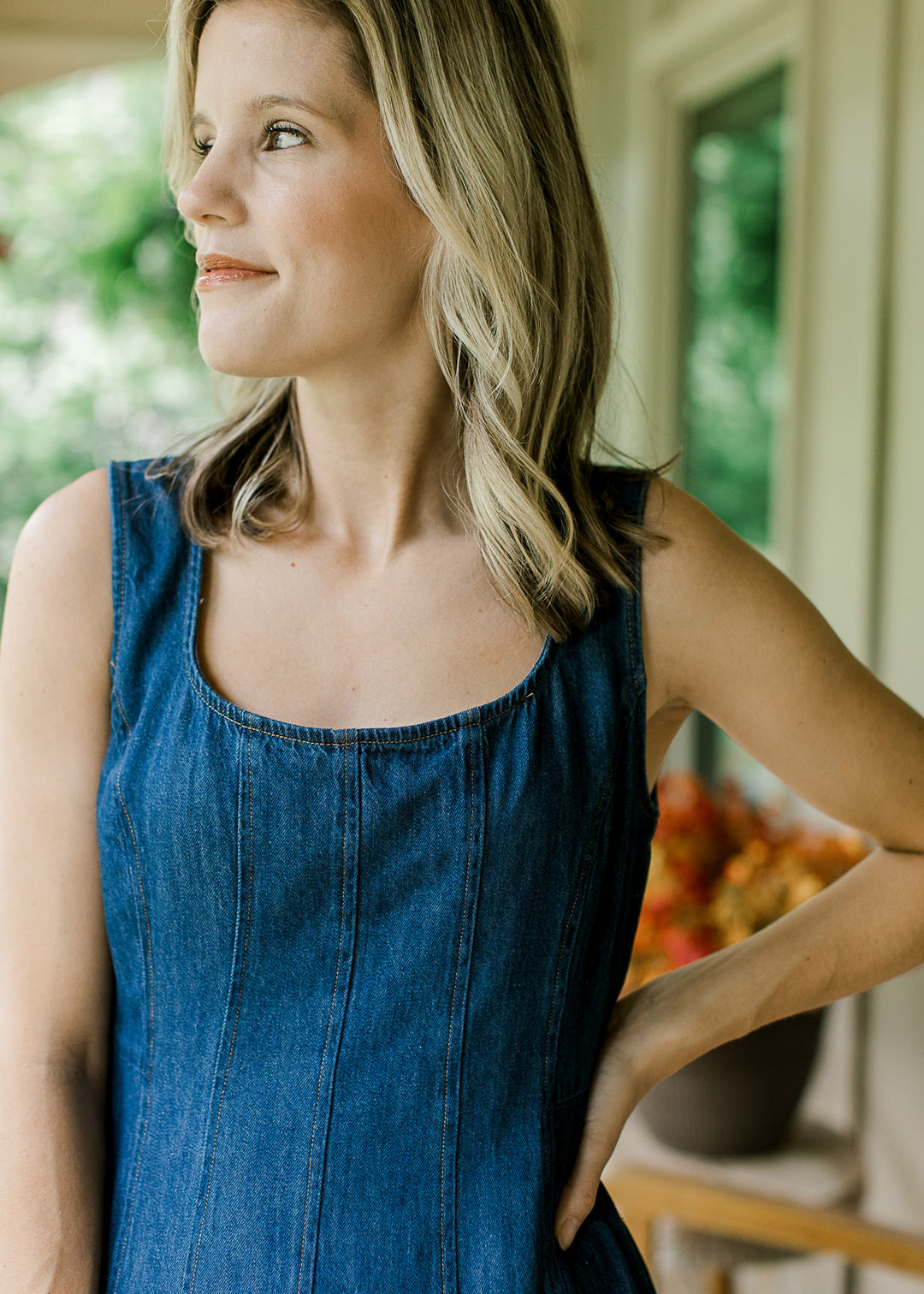 Close up of scoop neckline with panel design on a dark wash, sleeveless midi dress. 