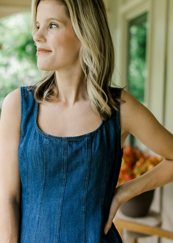 Close up of scoop neckline with panel design on a dark wash, sleeveless midi dress. 