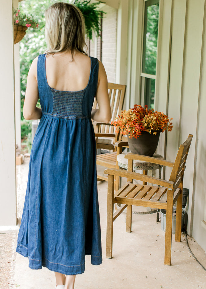 Back view of Model wearing a sleeveless dark denim midi with scoop neck and a smocked back. 