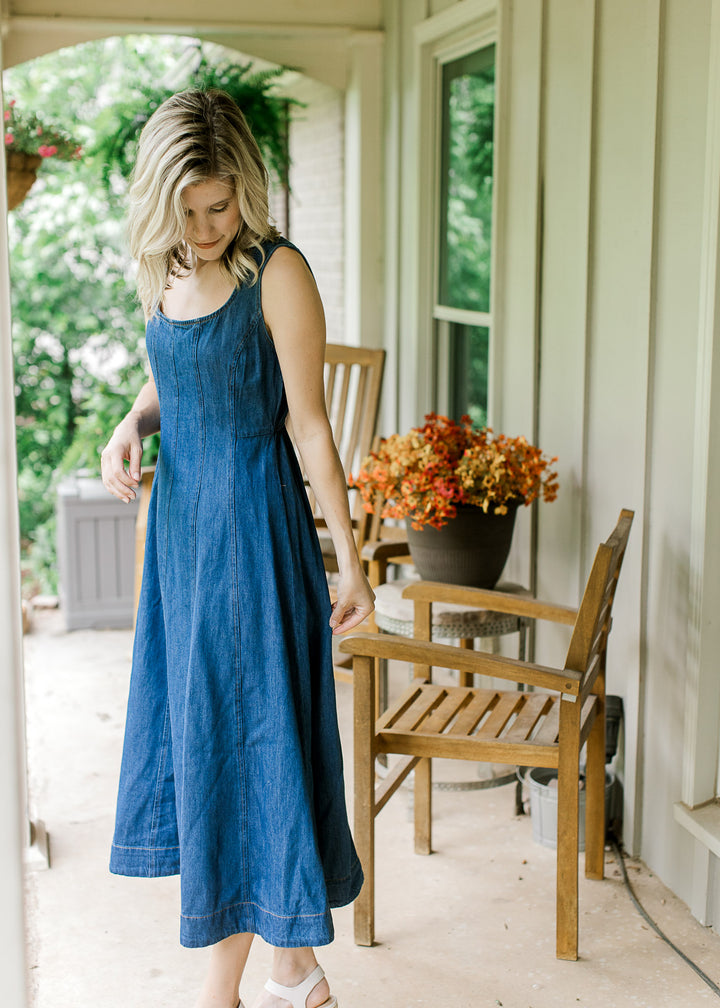 Model wearing heels and a sleeveless dark denim midi with scoop neck and a panel design.