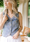 Model wearing a medium wash denim vest with a four button closure, V-neck and patch pockets.