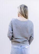 Back view of Model wearing a soft heather gray sweater with and long sleeves.