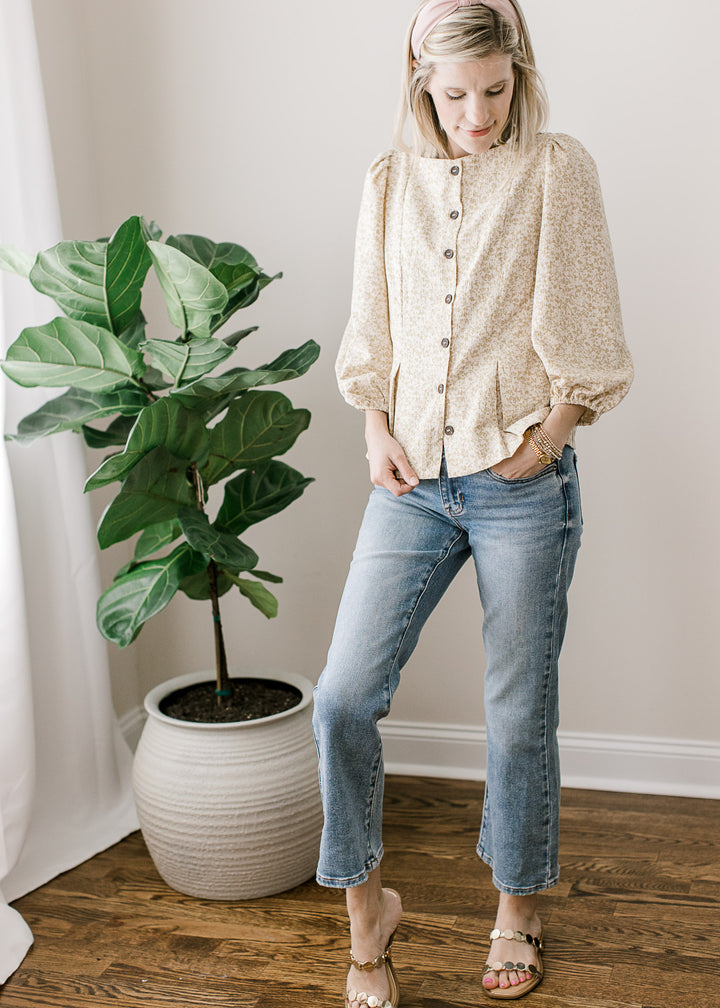 Model wearing a white top with taupe ditsy floral, boat neck, button-front and 3/4-bubble sleeves. 